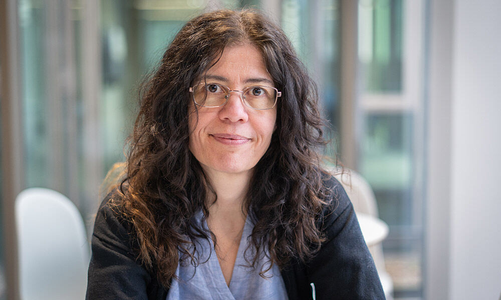 Close-up of smiling woman with glasses and long, dark, wavy hair. Person featured is called Aybuke Kupcu Yoldas. Photo credit: Jeff Dowling.